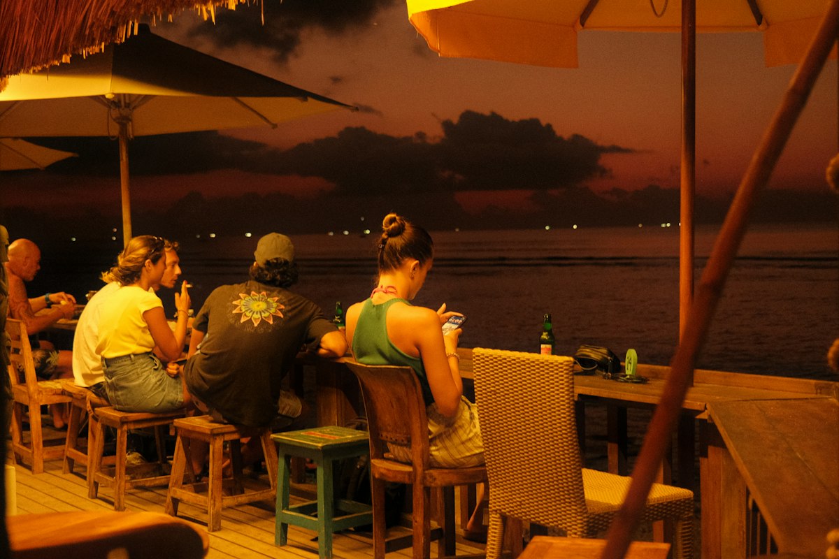 People sitting at a seaside bar at dusk (illustrative photo)