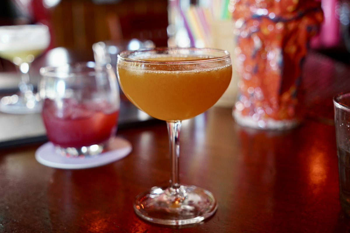 Cocktail in a coupe glass on a warmly lit bar (illustrative photo)